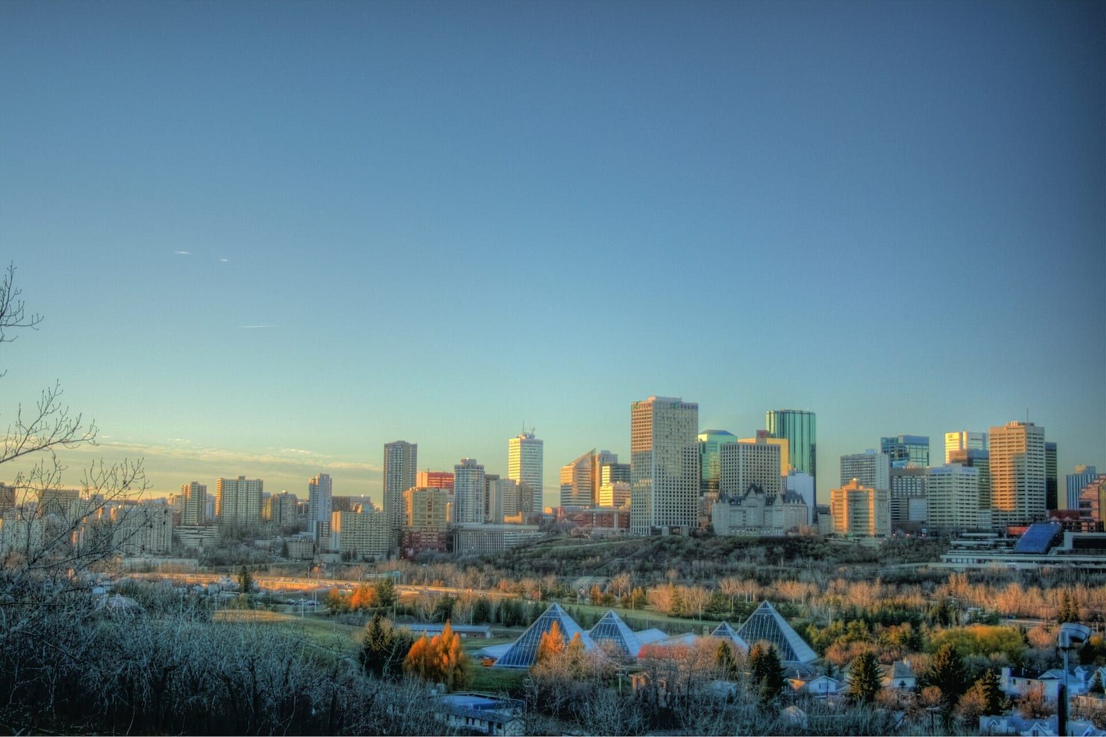 Downtown Edmonton skyline behind the Muttart Conservatory pyramids at dusk